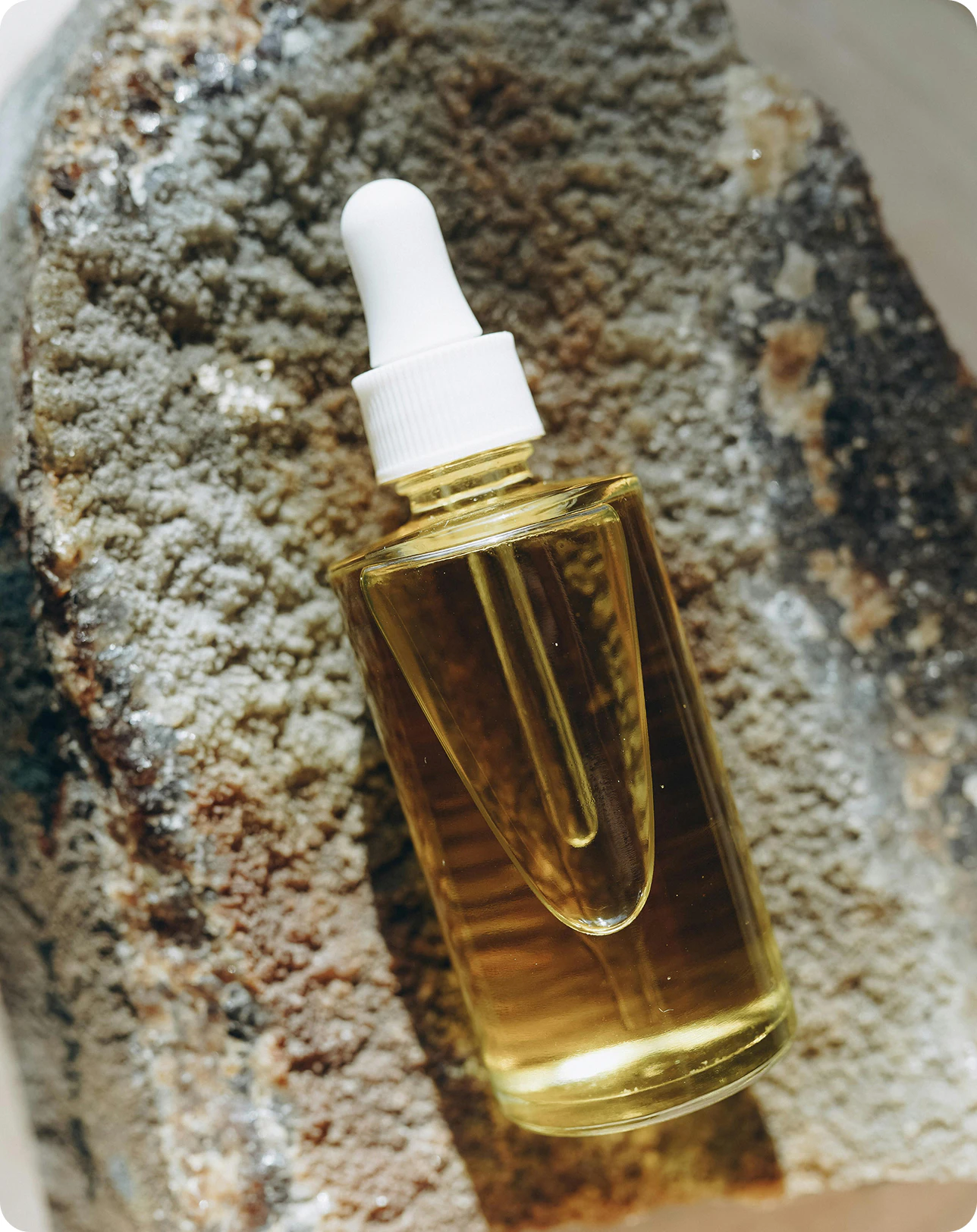 Un frasco cuentagotas de aceite sobre una piedra