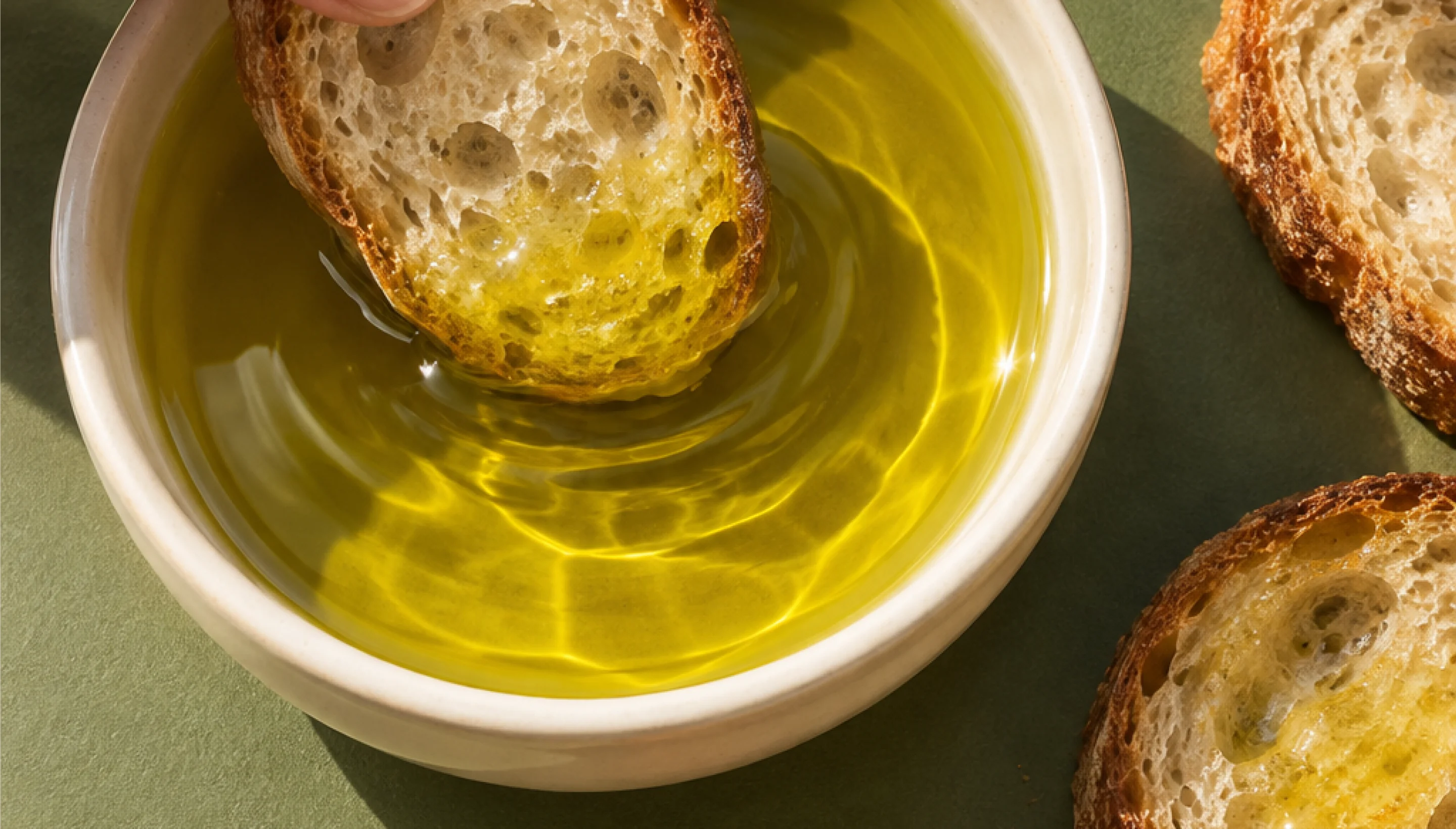 Bread dipped in olive oil, in a bowl on a green background