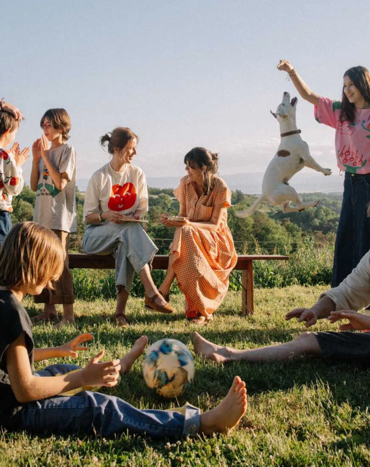 Families having a picnic outdoors, with a dog jumping